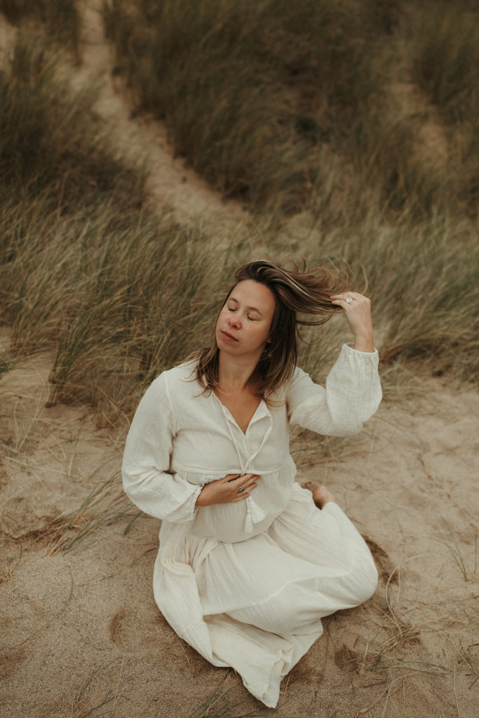pregnant woman sitting on beach