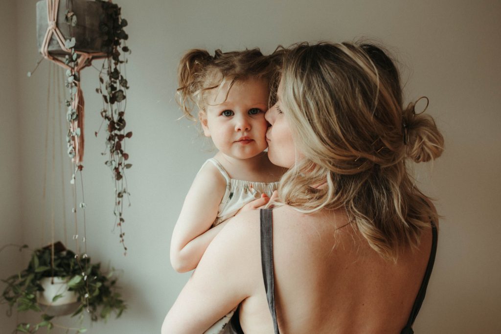 portrait photographer cornwall toddler being lifted by mum while being photographed at a family session at home