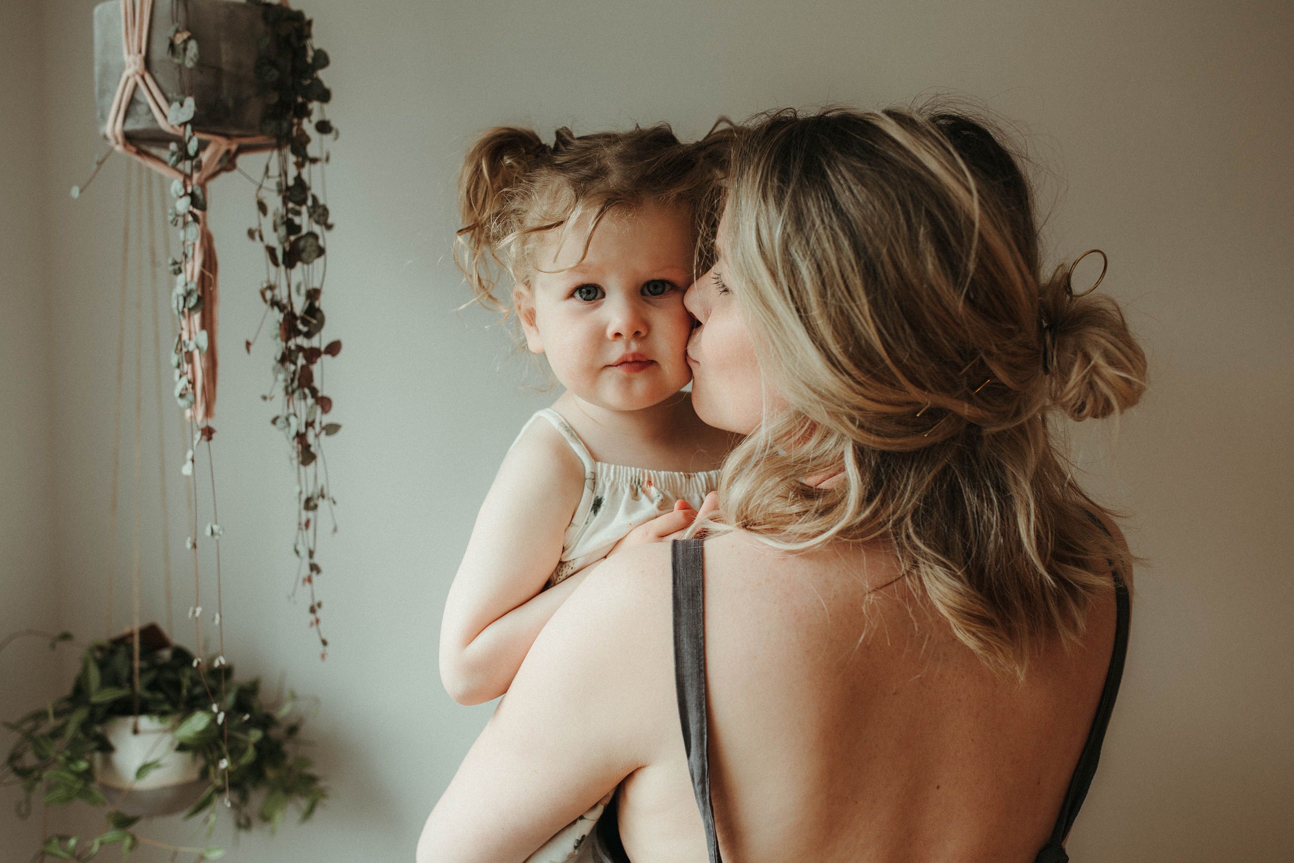portrait photographer cornwall toddler being lifted by mum while being photographed at a family session at home