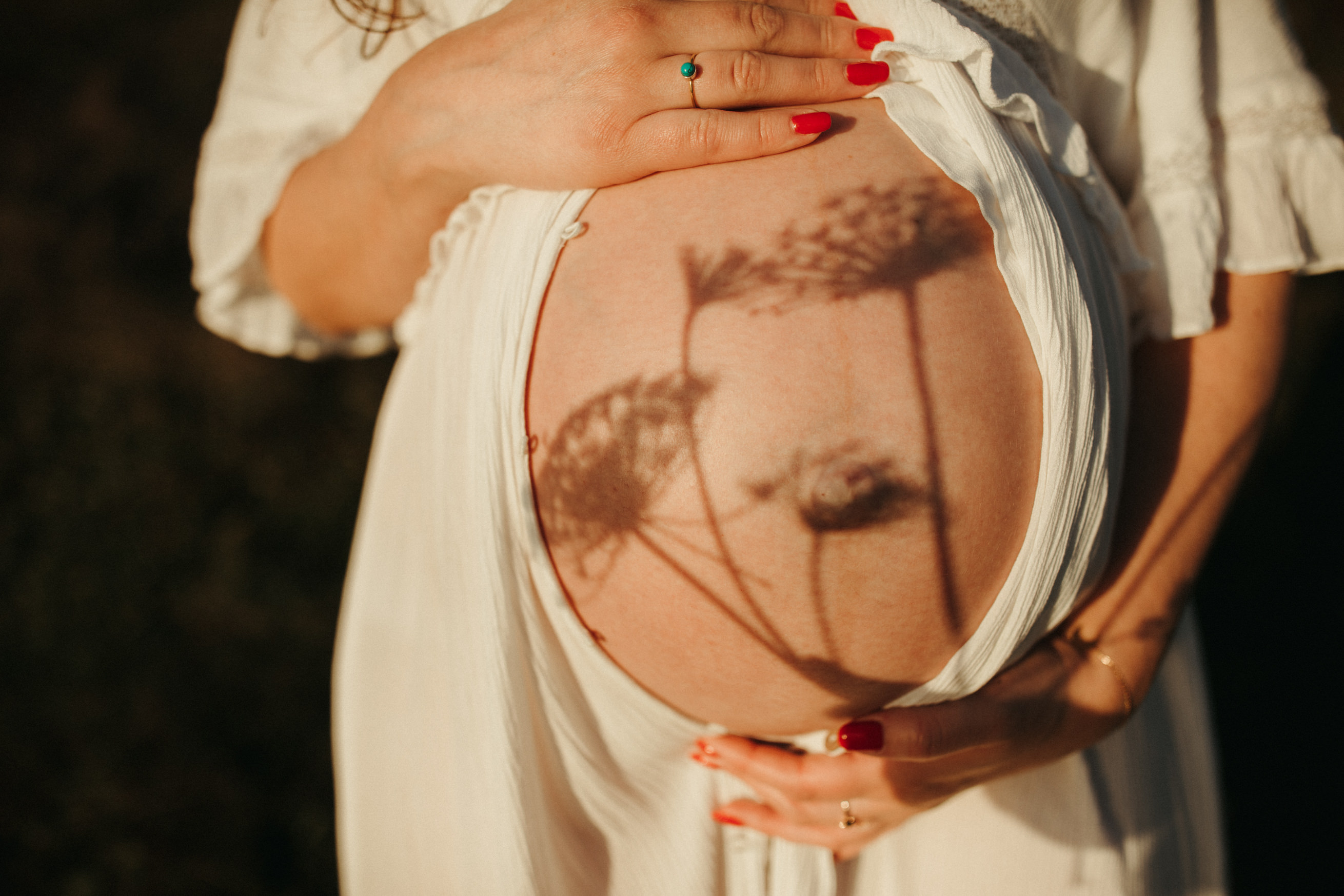 Shadows fall on  close up shot of pregnant belly Maternity and Newborn Photographer Devon