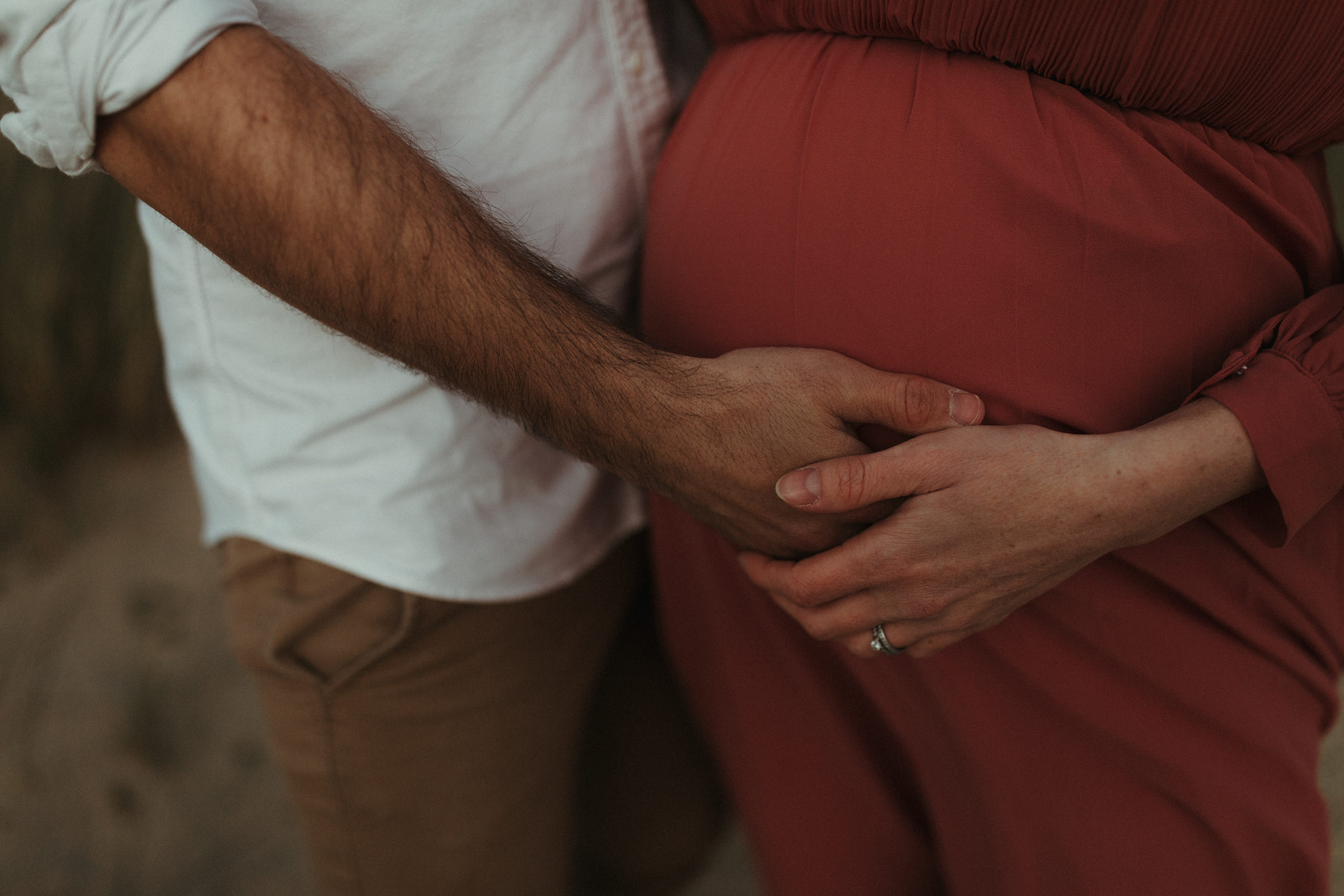 close up of mans hand on wife's stomach maternity
