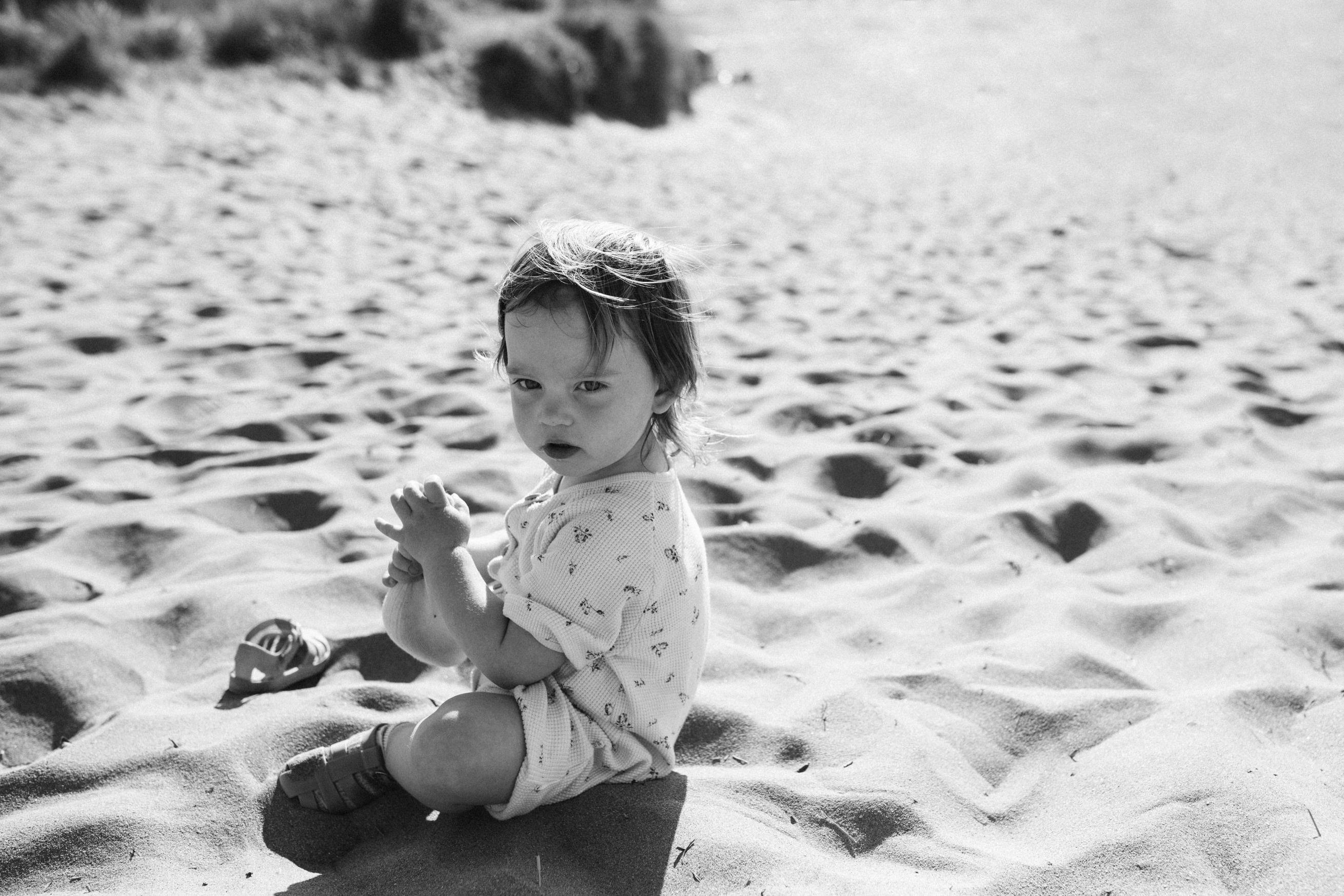 black and white shot of toddler on beach looking at the camera Beach Family Photoshoot