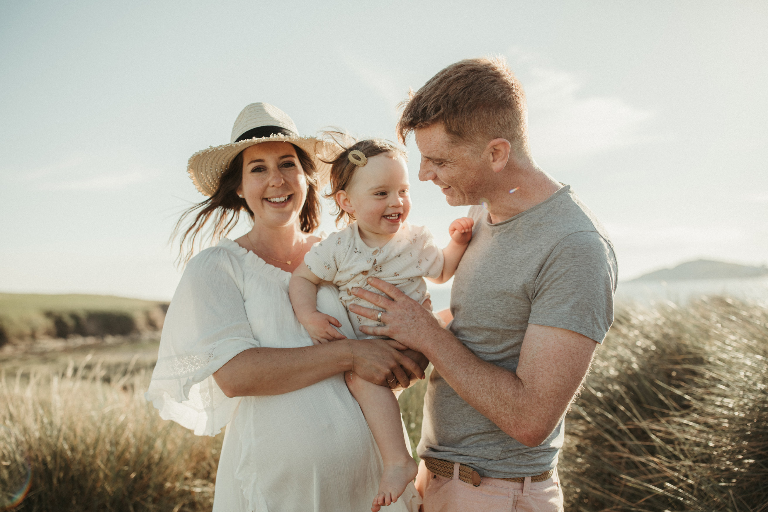 Mother and Father hold toddler in the sane dunes Beach Family Photoshoot