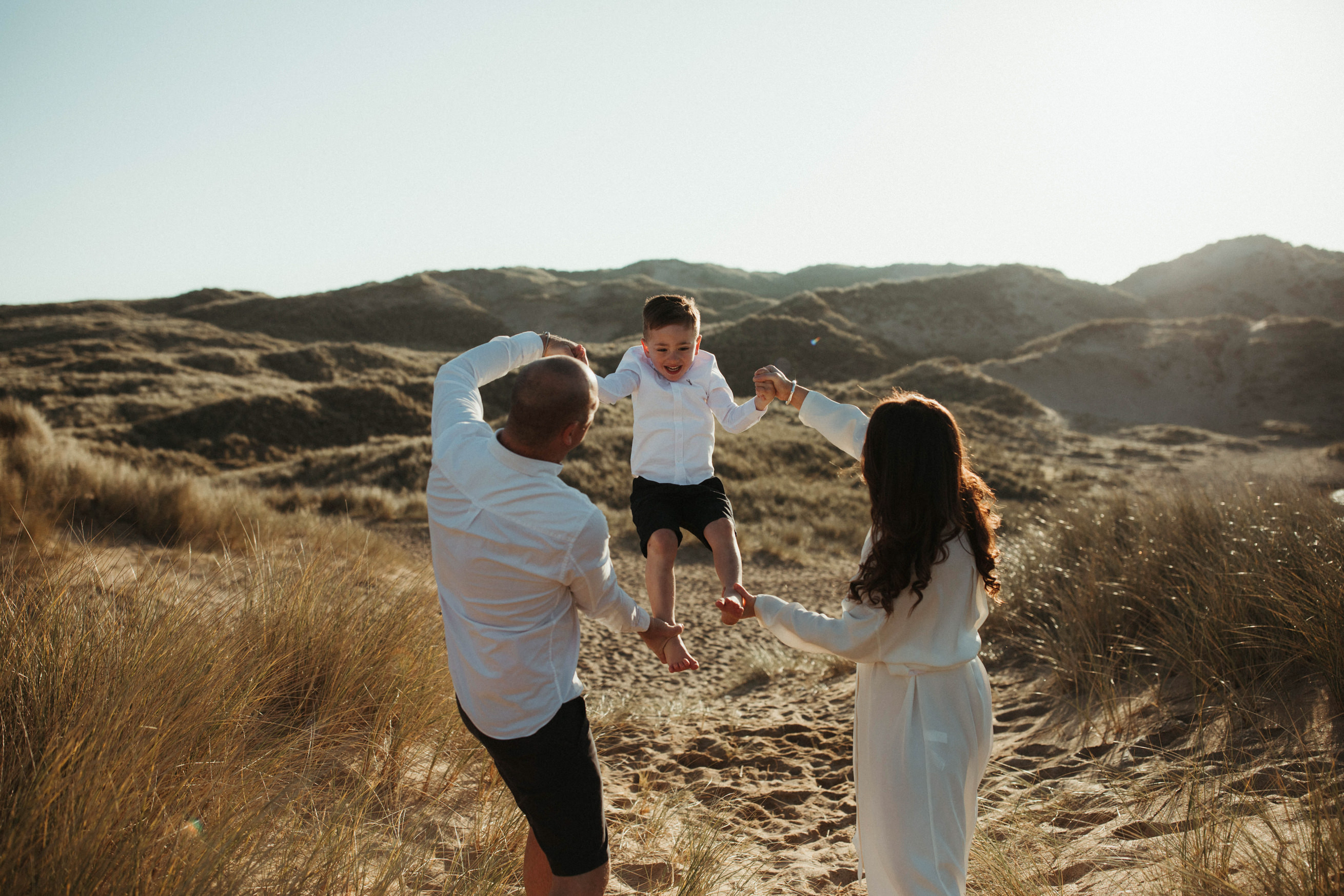 mum and dad swing son in the sand dunes