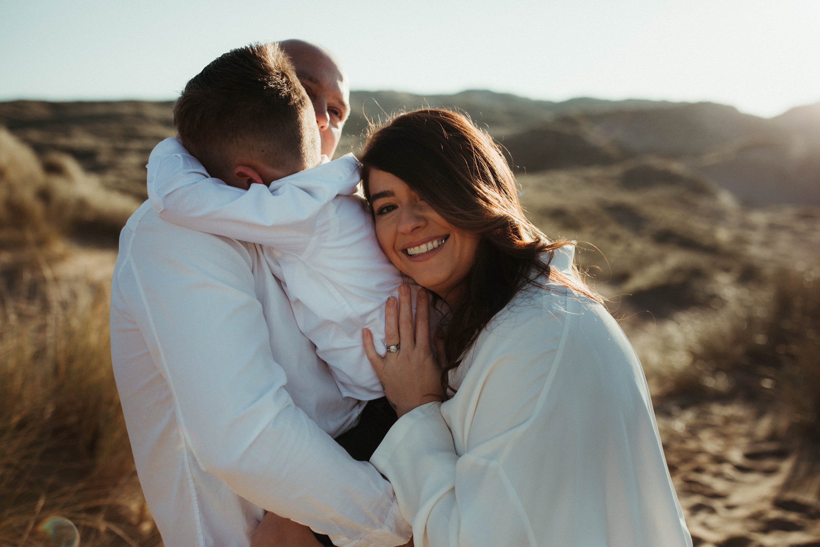 family cuddles on the beach and mum smiles into camera Family Lifestyle Photography