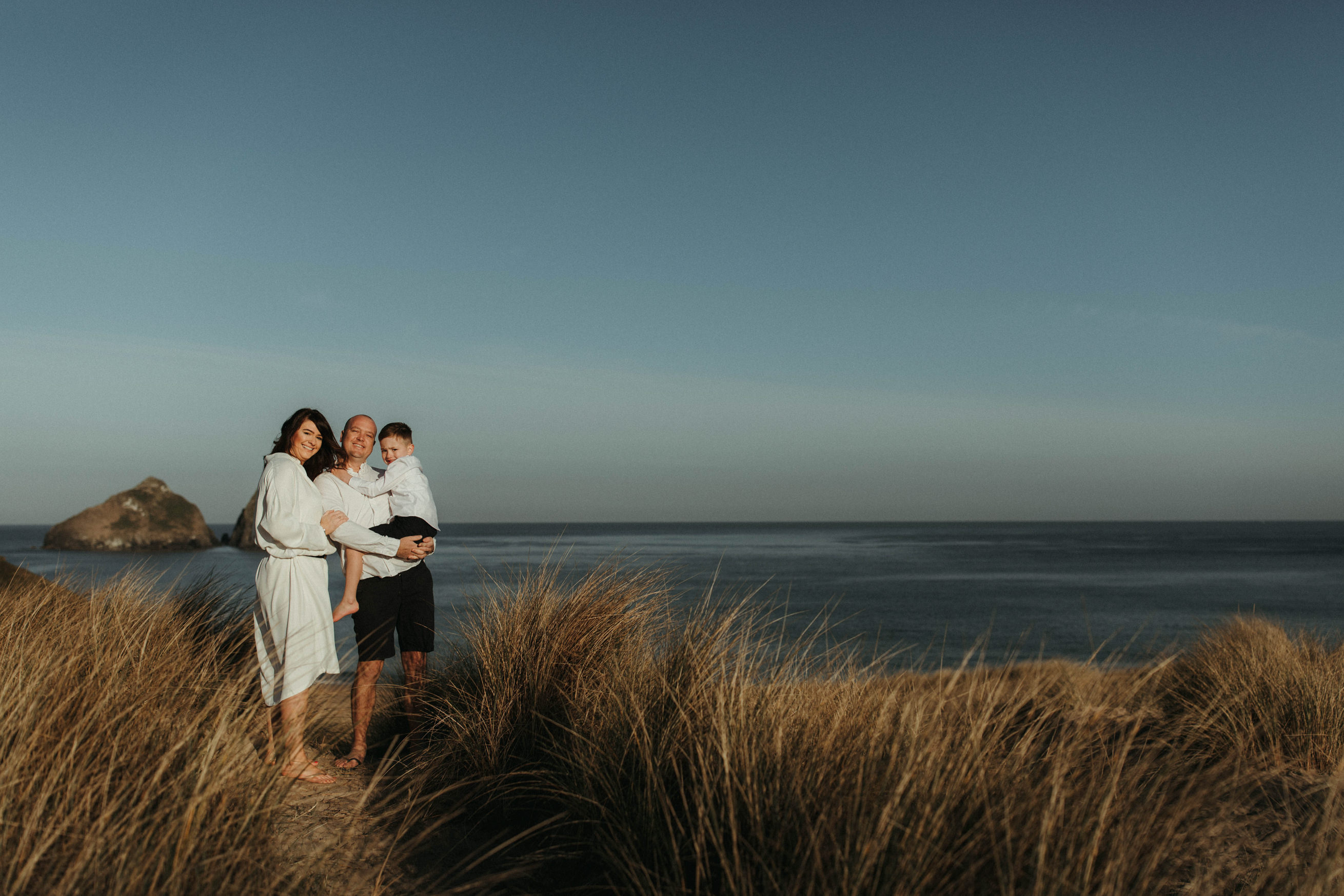 family smile at camera with sea in the background at holywell bay Family Lifestyle Photography