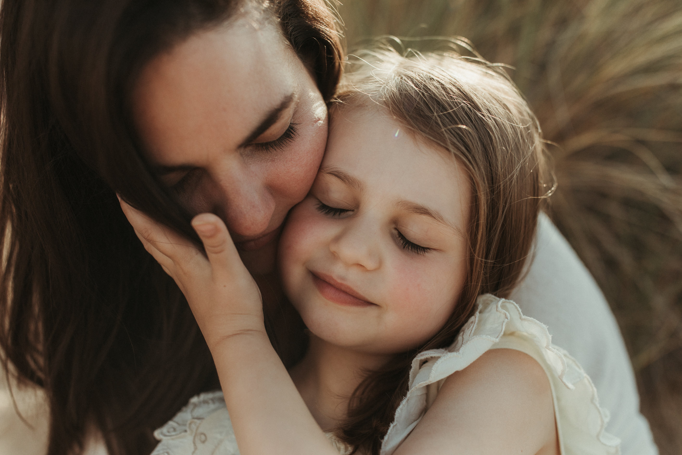 daughter closes eyes and holds on to mothers face