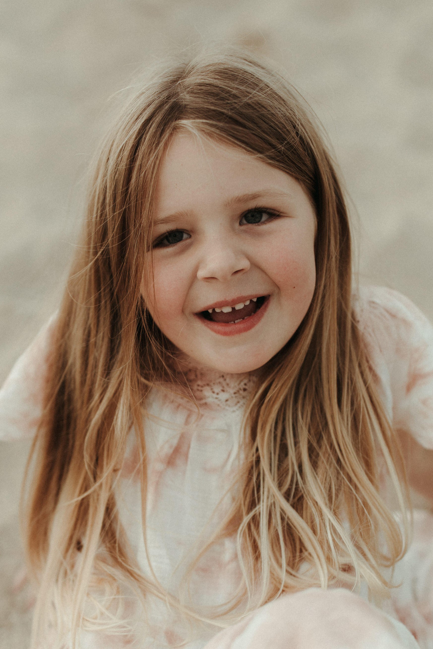 little girl with long hair smiles at camer for boho family photos