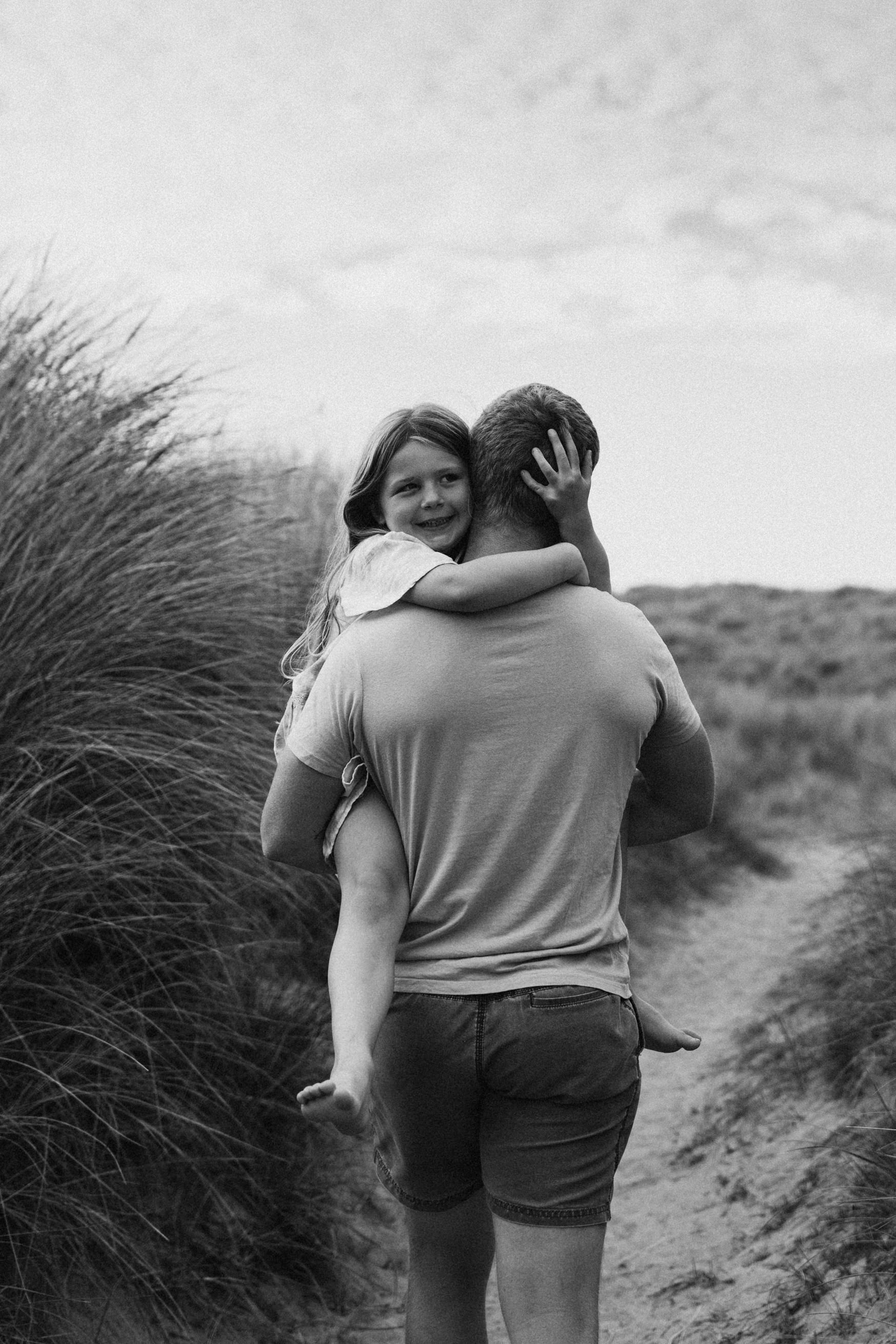dad walks away from camera holding his daughter