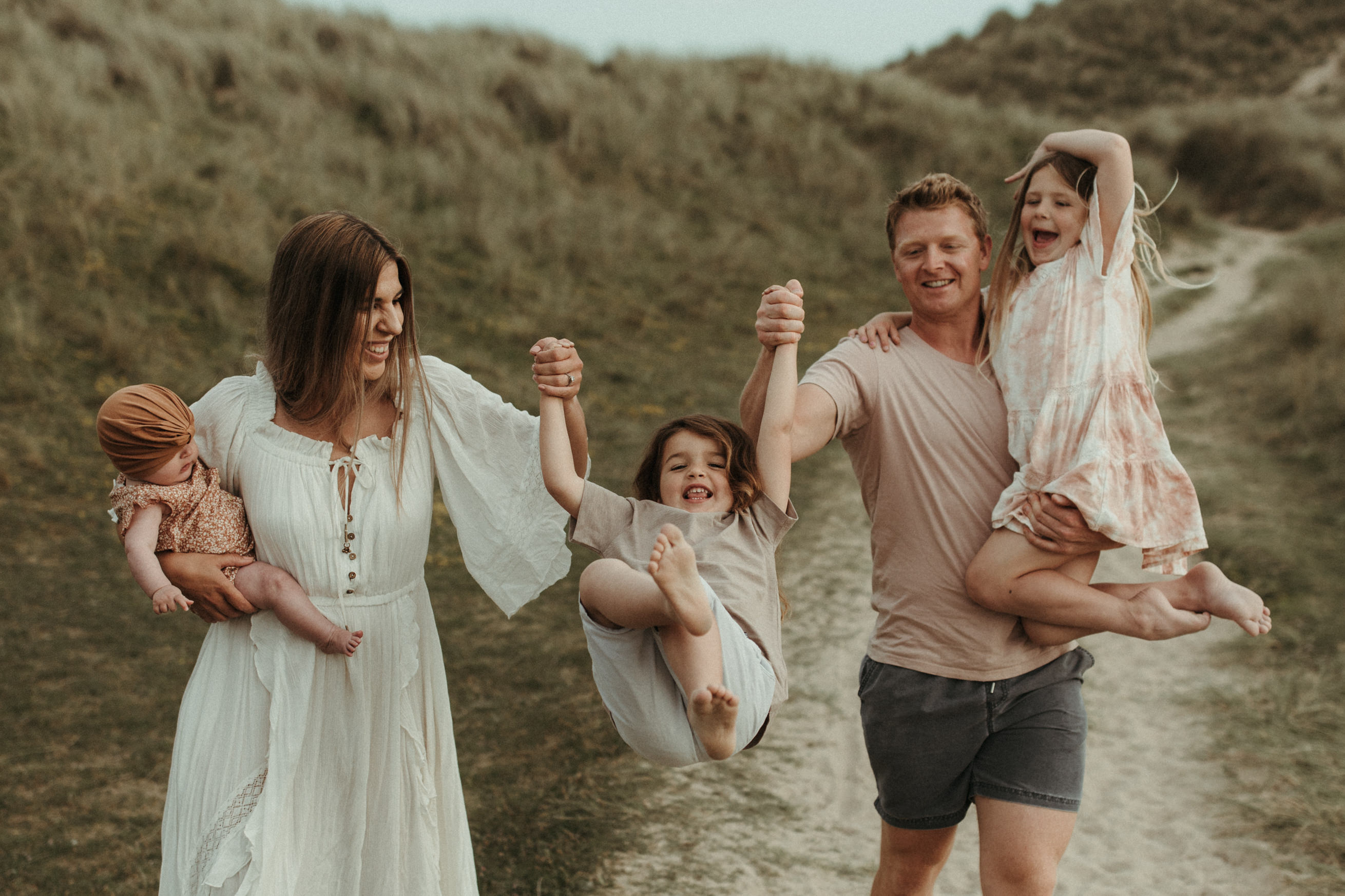 family walk towards camera swinging middle child